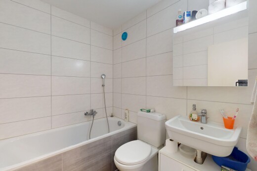 salle de bains avec évier, mur en carrelage, salle de bain complète, bain, et toilette