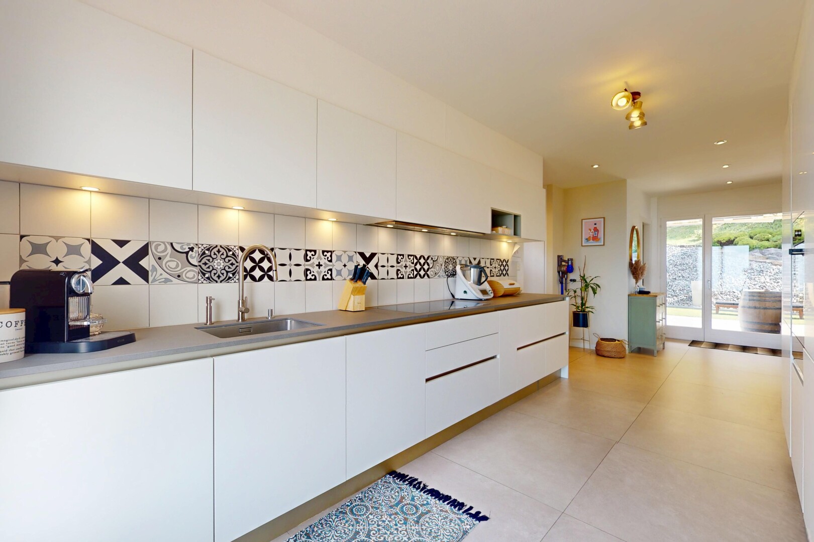 kitchen featuring backsplash, modern cabinets, white cabinetry, and light tile patterned floors