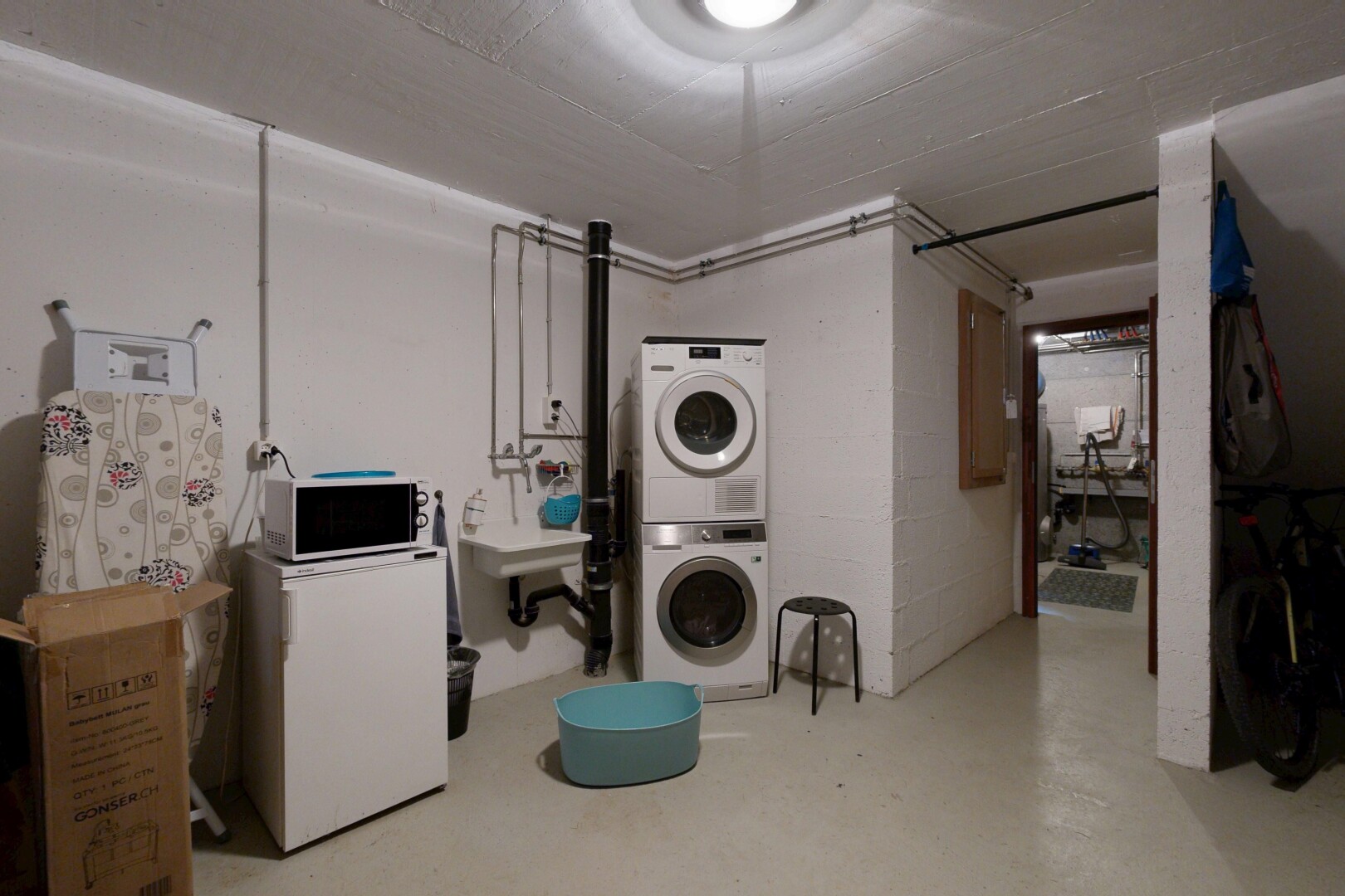 buanderie avec sous-sol, lave-linge et sèche-linge superposés, sol en béton, concrete floor, et inside property