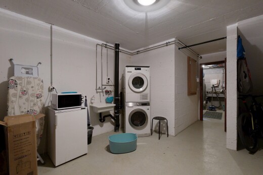 buanderie avec sous-sol, lave-linge et sèche-linge superposés, sol en béton, concrete floor, et inside property