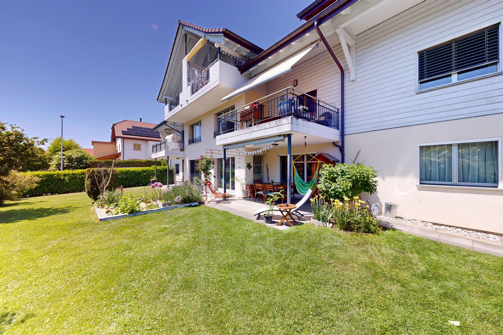 façade avec property visible, bardage horizontal, pelouse, balcon, et terrasse