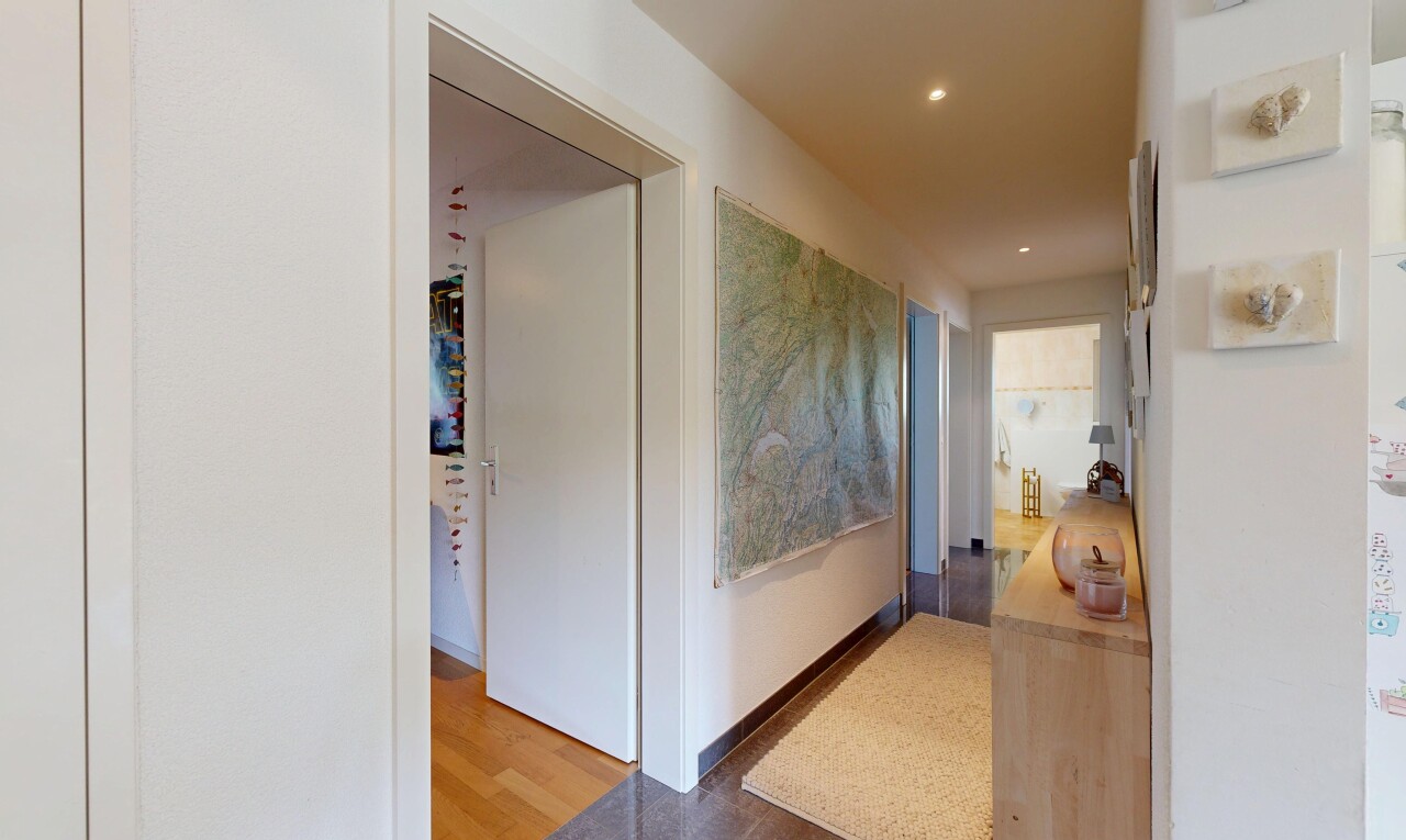 couloir avec inside community, wood finish floor, sol en finition bois, drywall, et cloison sèche