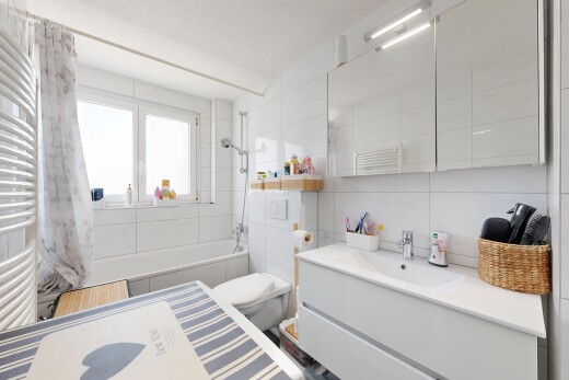 salle de bains avec chauffe-serviettes, salle de bain complète, miroir, lavabo (ou coiffeuse selon le contexte), et mur en carrelage