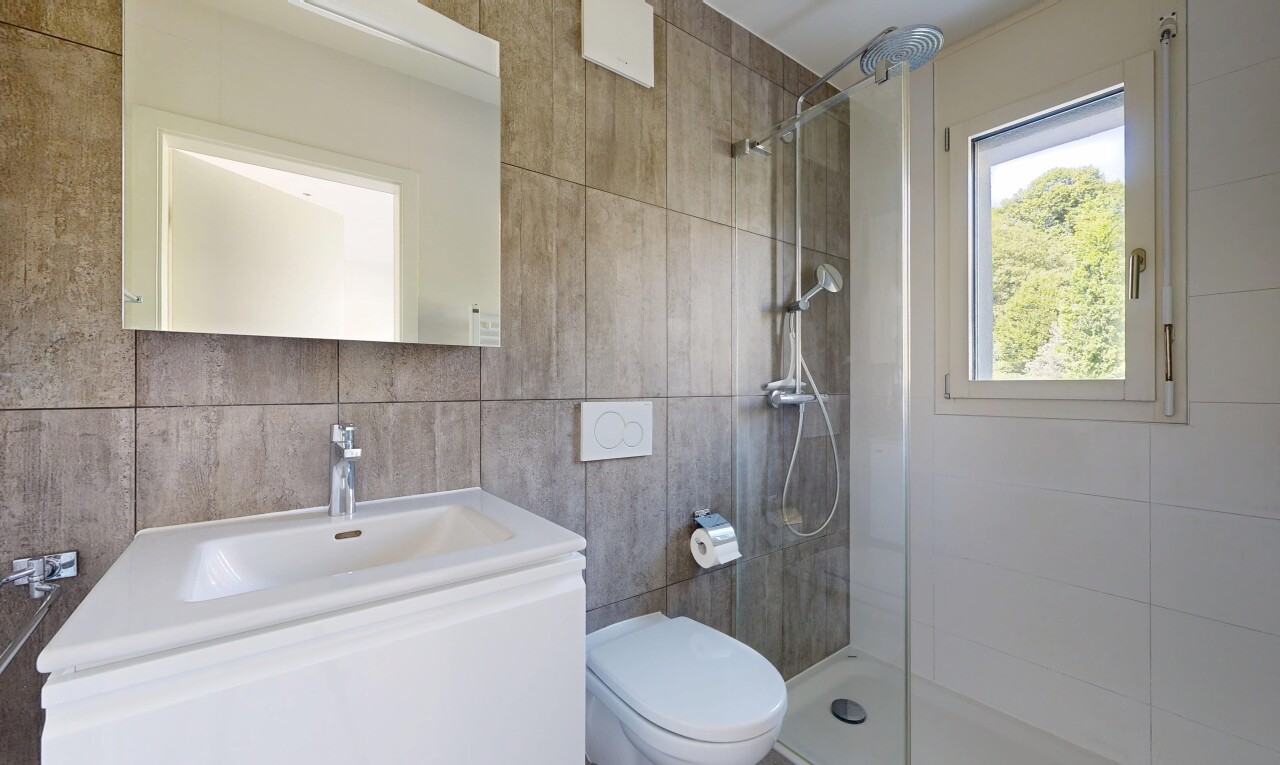 full bath featuring walk in shower, tile walls, and vanity