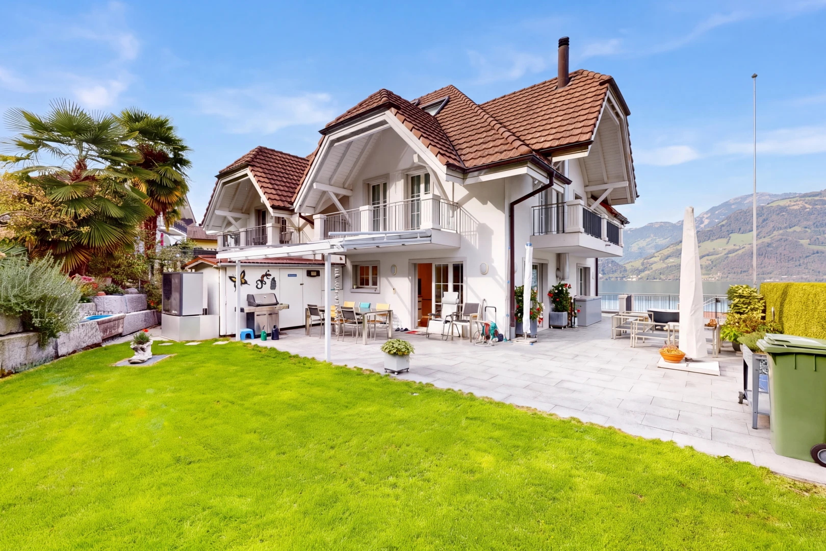 view of property featuring a balcony, a tiled roof, a patio, and a lawn