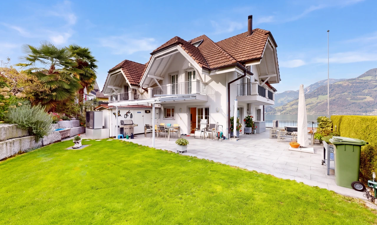 view of property featuring a balcony, a tiled roof, a patio, and a lawn