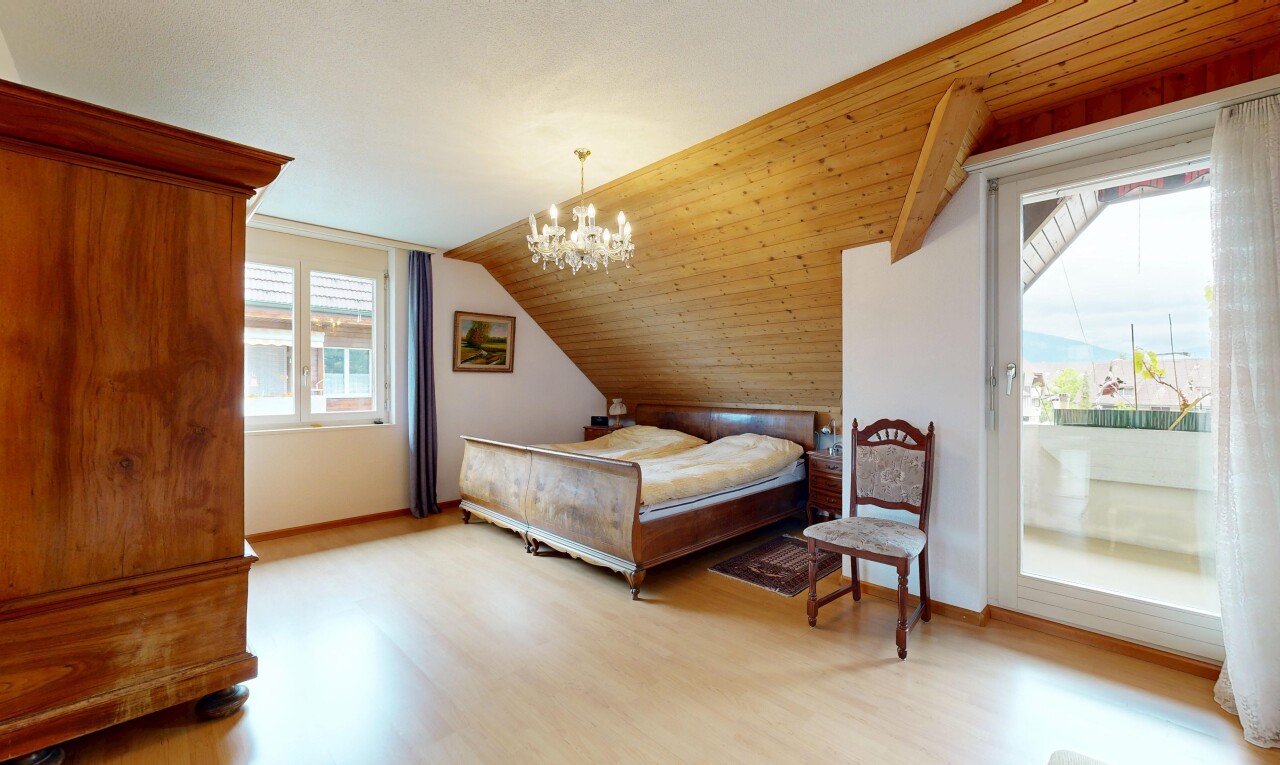zimmer / schlafzimmer mit holzfußboden, wood finish floor, inside property, bemerkenswerter kronleuchter, und dachschräge