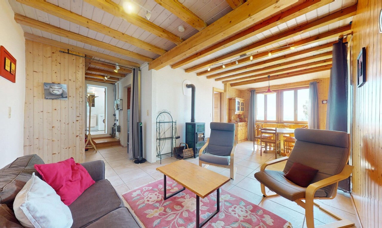 living / dining room with wooden walls, light tile patterned flooring, a wood stove, wooden ceiling, and beamed ceiling