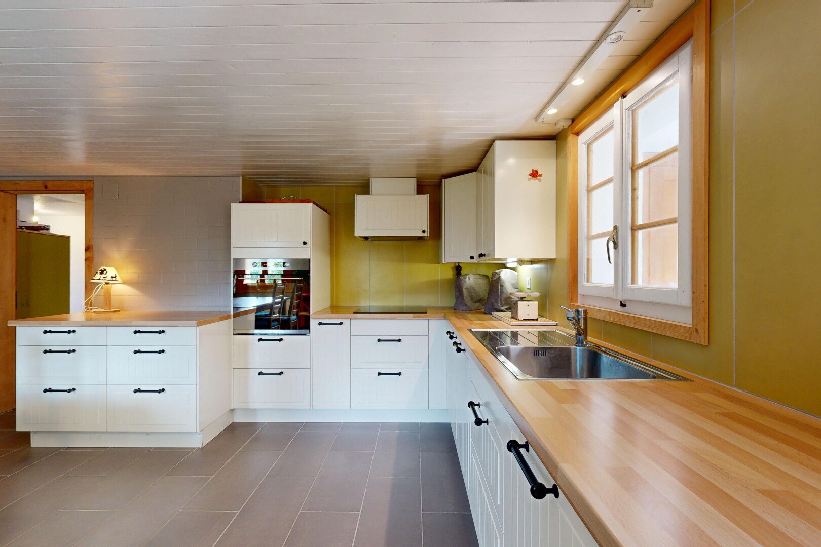 cuisine avec inside property, natural light, lumière naturelle, armoires blanches, et four