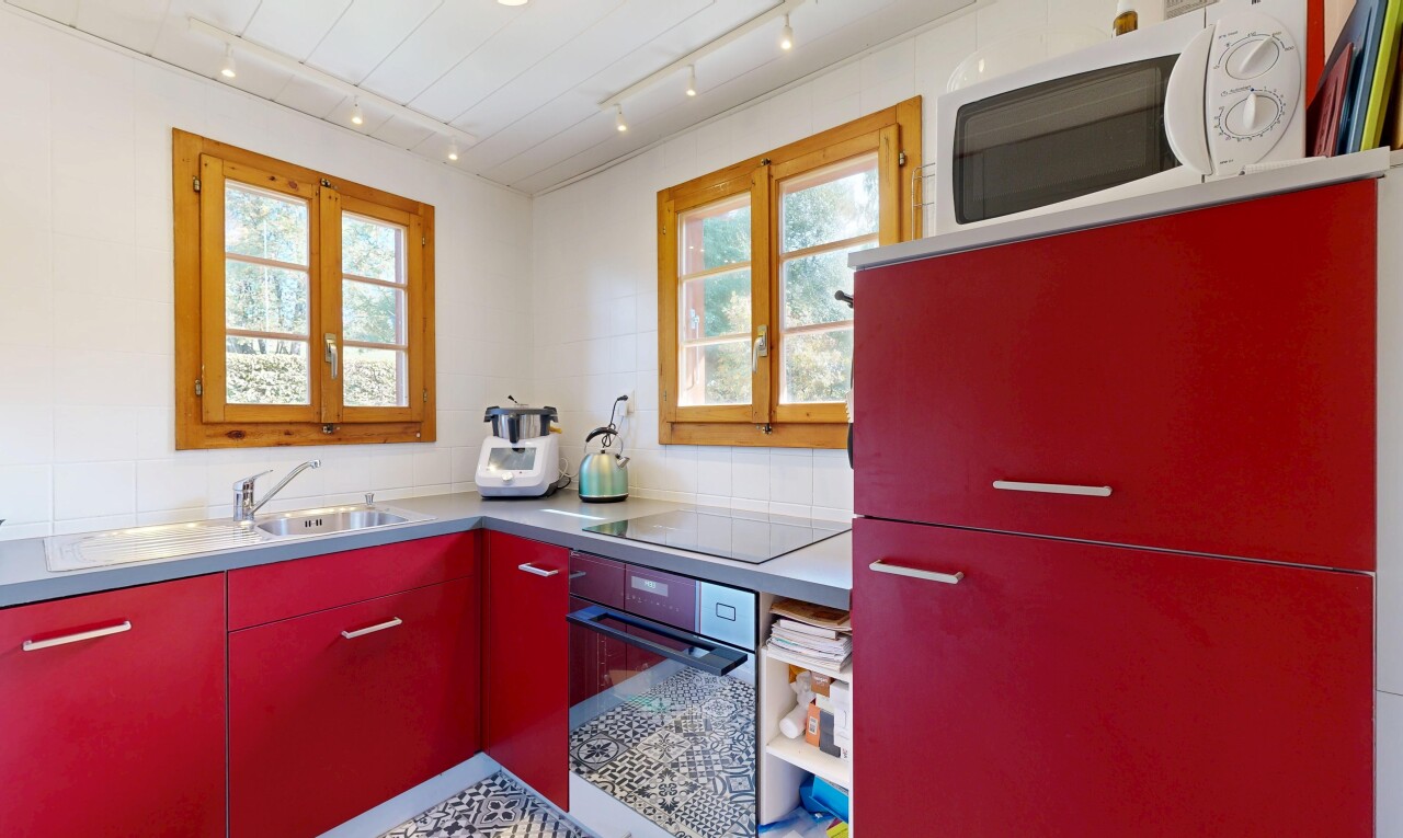 cuisine avec armoires rouges, four, micro-ondes, inside property, et natural light