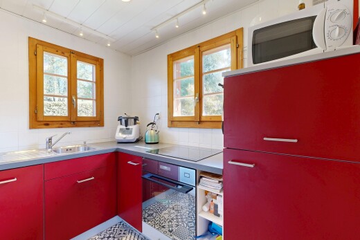 cuisine avec armoires rouges, four, micro-ondes, inside property, et natural light