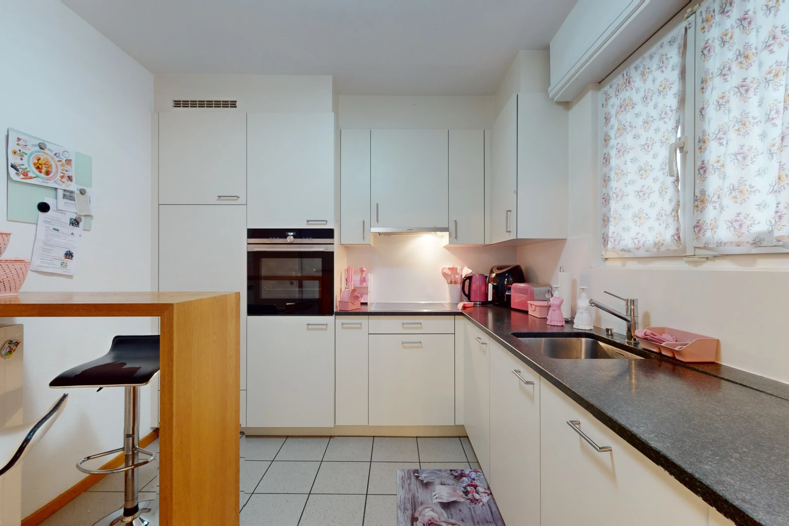 küche mit waschbecken, hellen fliesenböden, ofen und weissen schränken