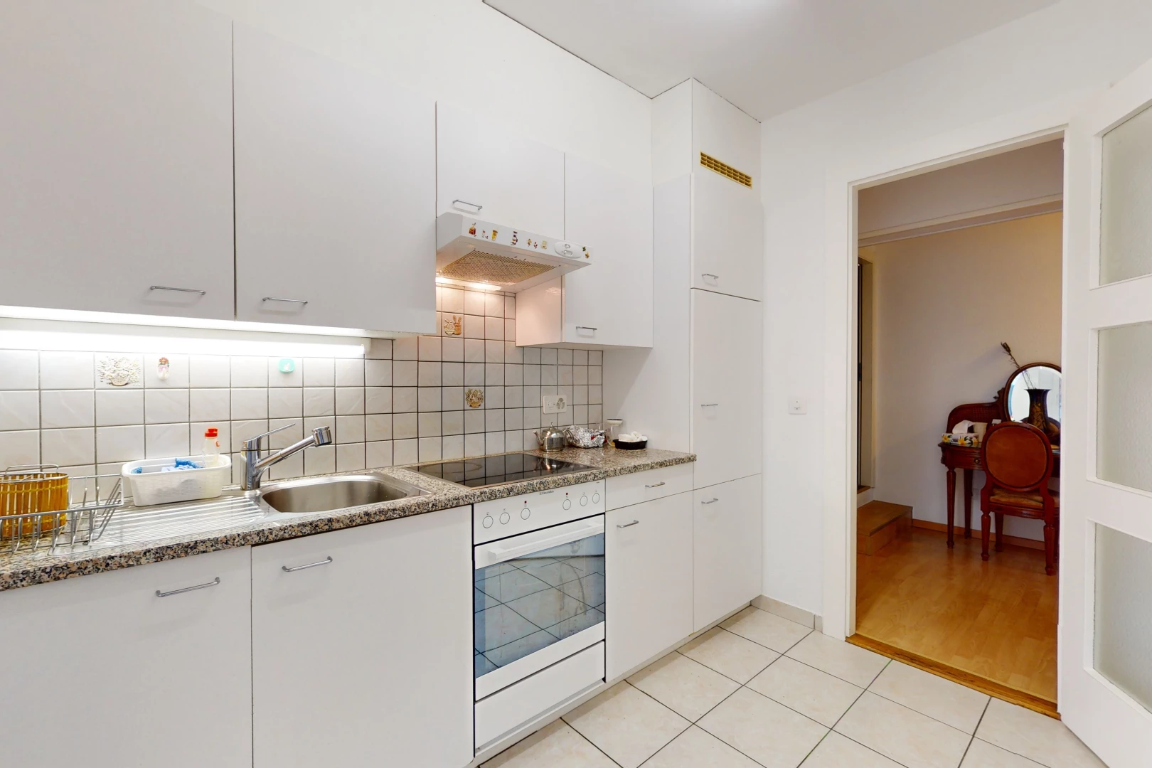 küche mit schwarzem elektrischem kochfeld, heller holzboden, weiß