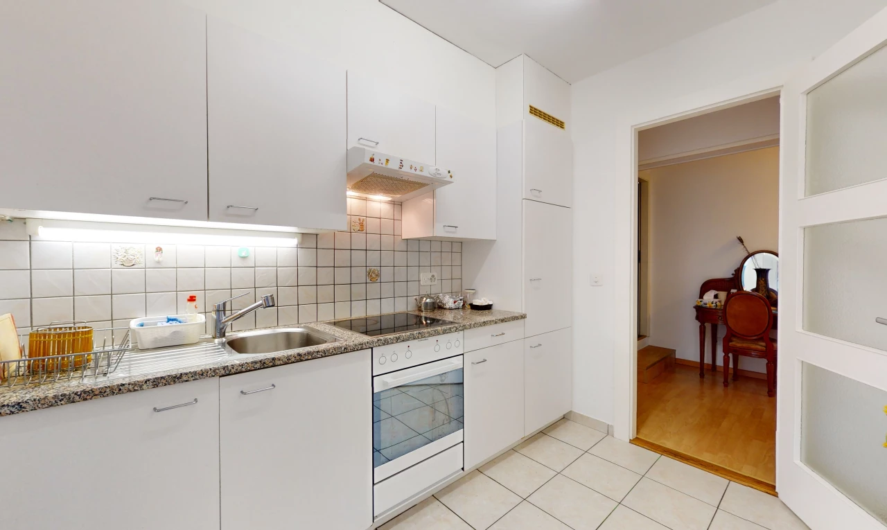 küche mit schwarzem elektrischem kochfeld, heller holzboden, weiß