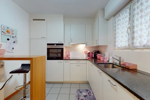 küche mit waschbecken, hellen fliesenböden, ofen und weissen schränken