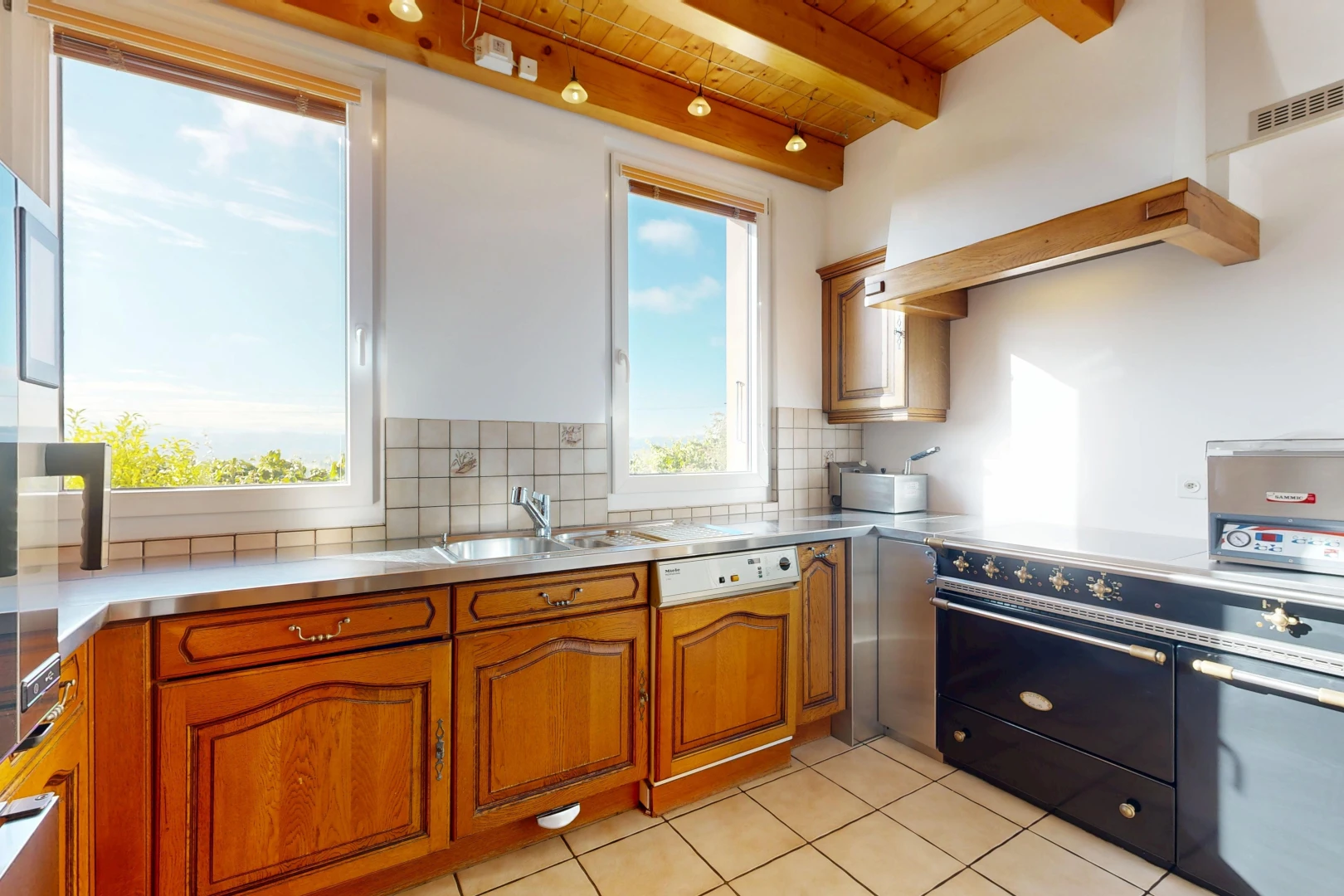 cuisine avec stainless steel countertops, plans de travail en acier inoxydable, éclairage sur rail, cuisinière, et raised cabinets