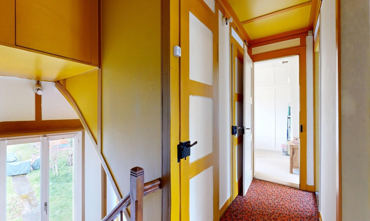 hall featuring dark carpet and an upstairs landing
