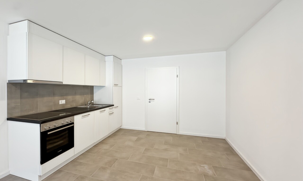cuisine avec dark countertops, plans de travail, four, light floor, et drywall