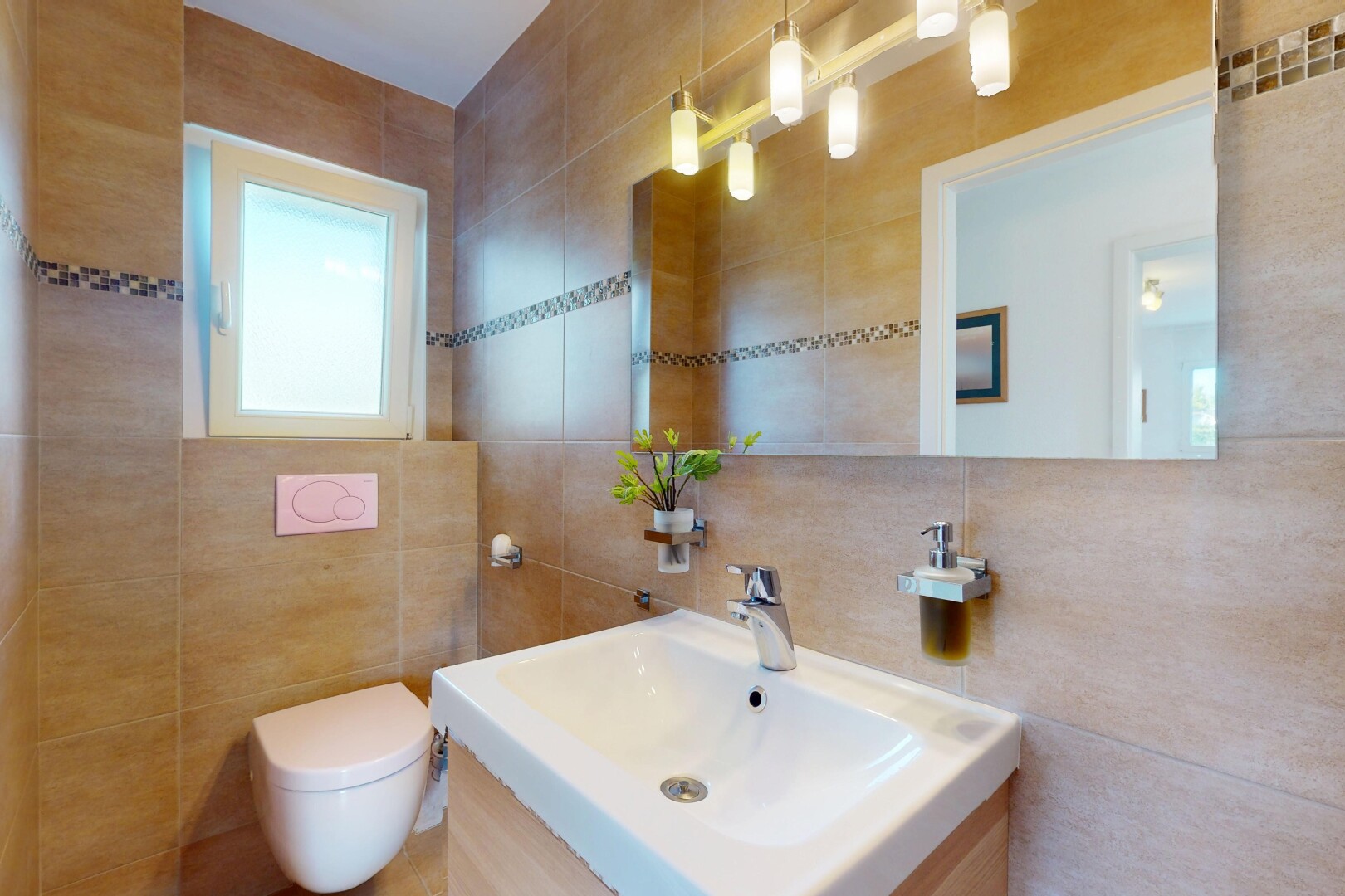 salle de bains avec miroir, mur en carrelage, lumière naturelle, toilette, et évier