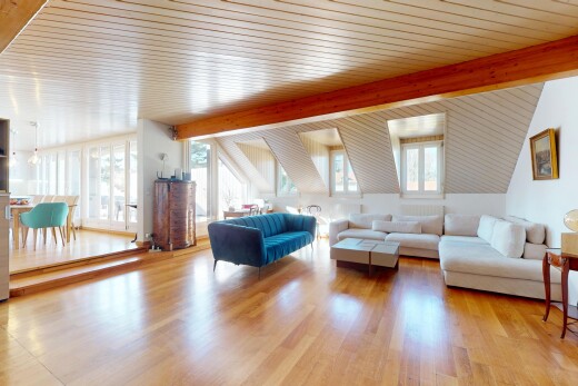 salon avec plafond voûté, lumière naturelle, plancher de bois, et poutres apparentes