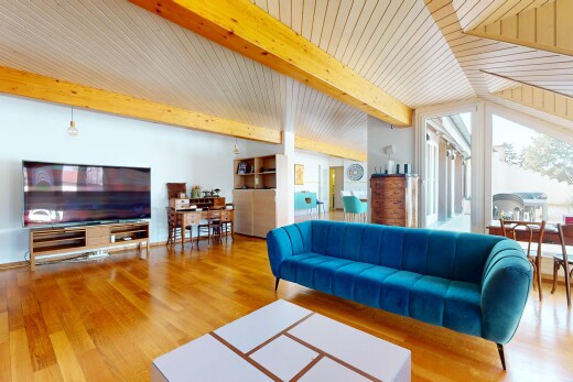 salon avec plancher de bois, plafond voûté, lumière naturelle, poutres apparentes, et télévision