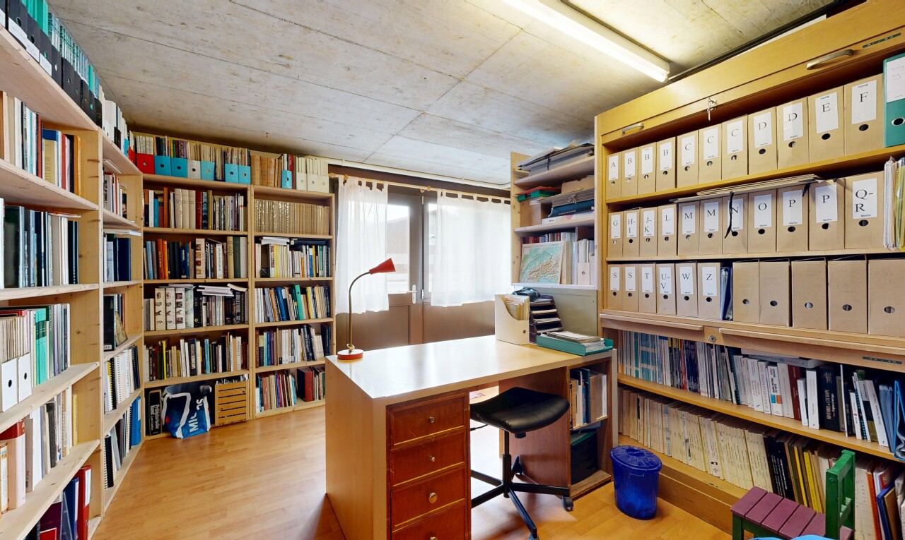 bureau avec wood finish floor, étagères intégrées, inside community, concrete ceiling, et light floor