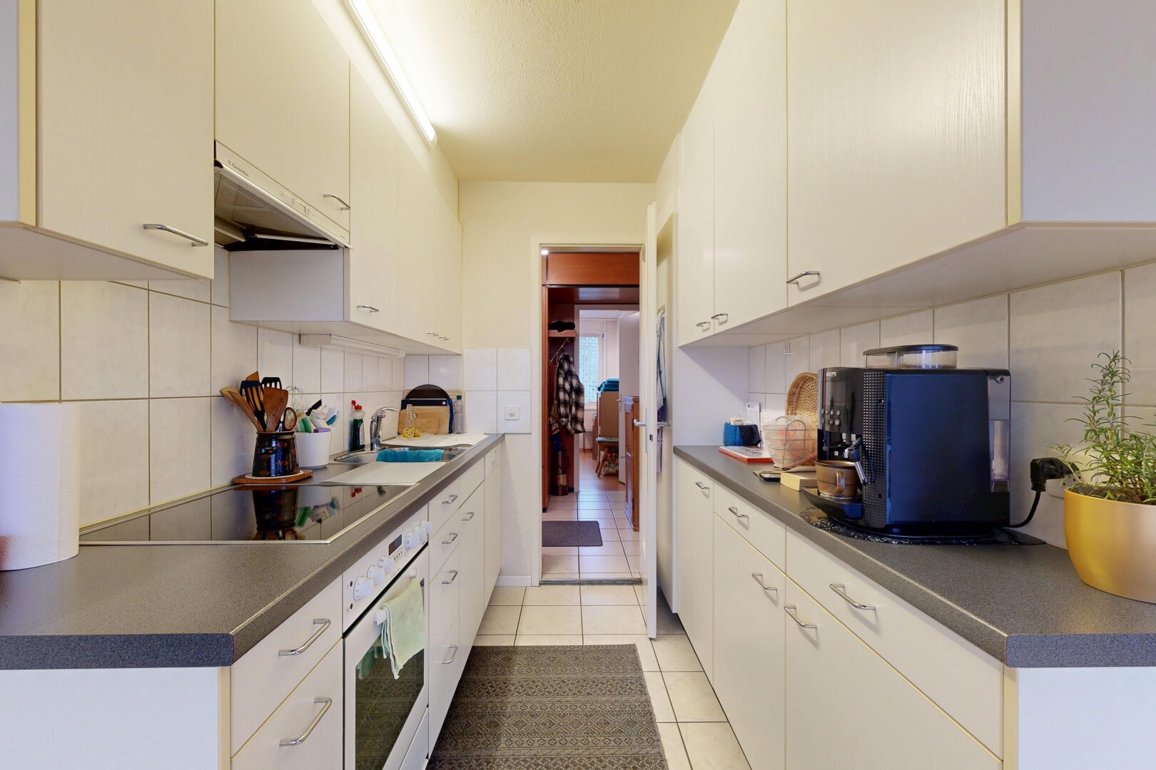 kitchen featuring dark countertops, light tile patterned floors, white oven, under cabinet range hood, and white cabinetry