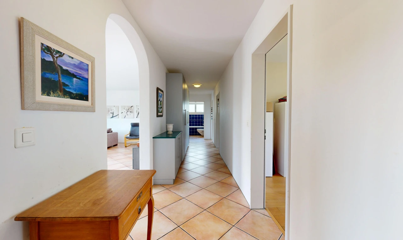 hall with arched walkways and light tile patterned flooring