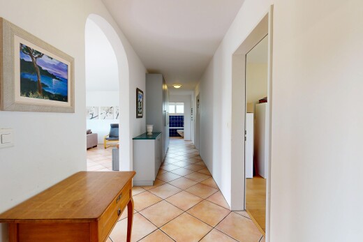 hall with arched walkways and light tile patterned flooring