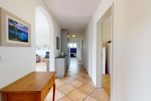 hall with arched walkways and light tile patterned flooring