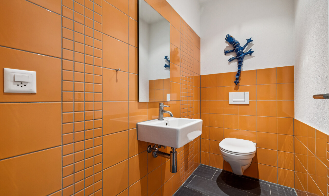 half bath with tile walls, wainscoting, and dark tile patterned floors