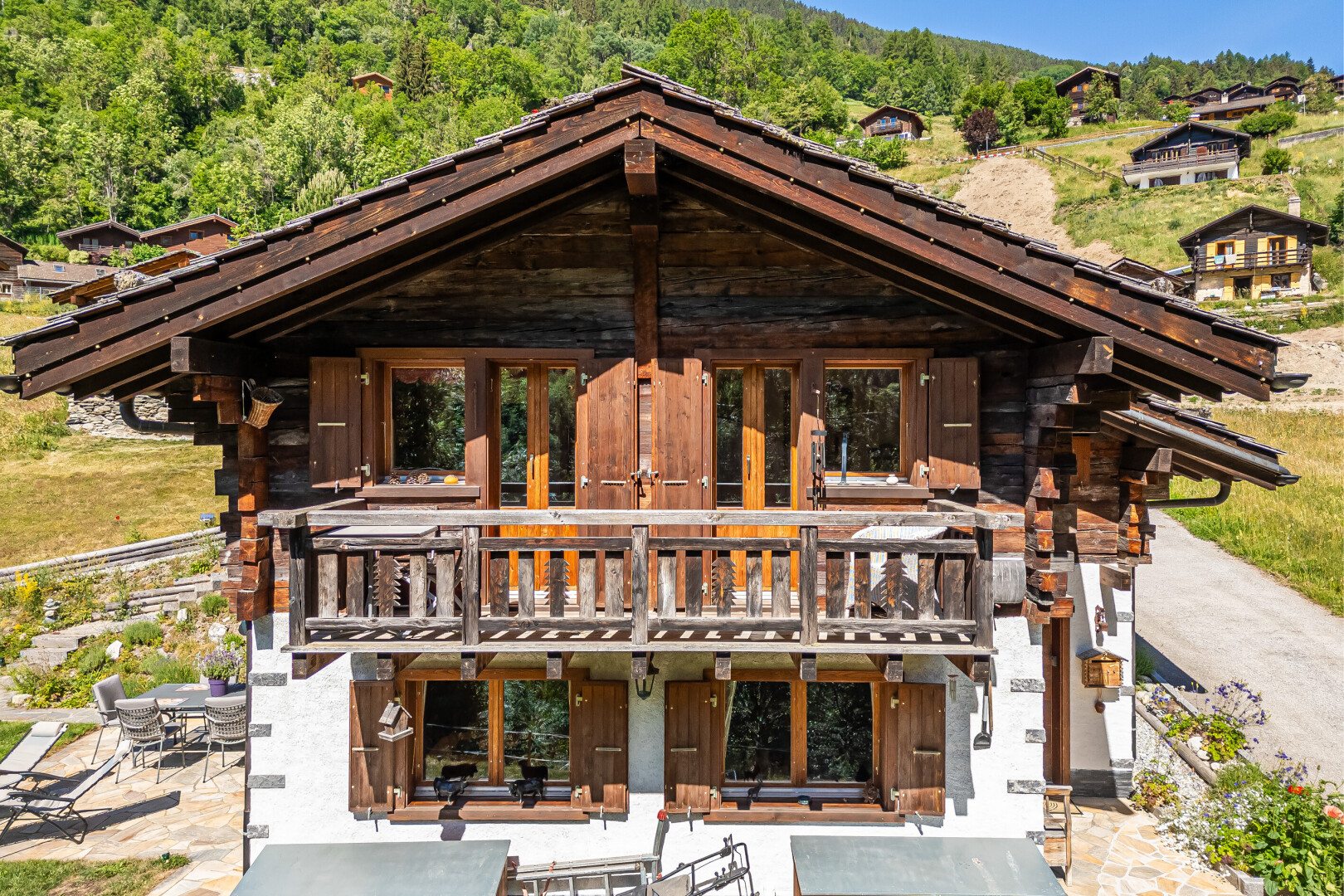 façade avec property visible, coin repas extérieur, terrasse, bardage en rondins, et portes-fenêtres