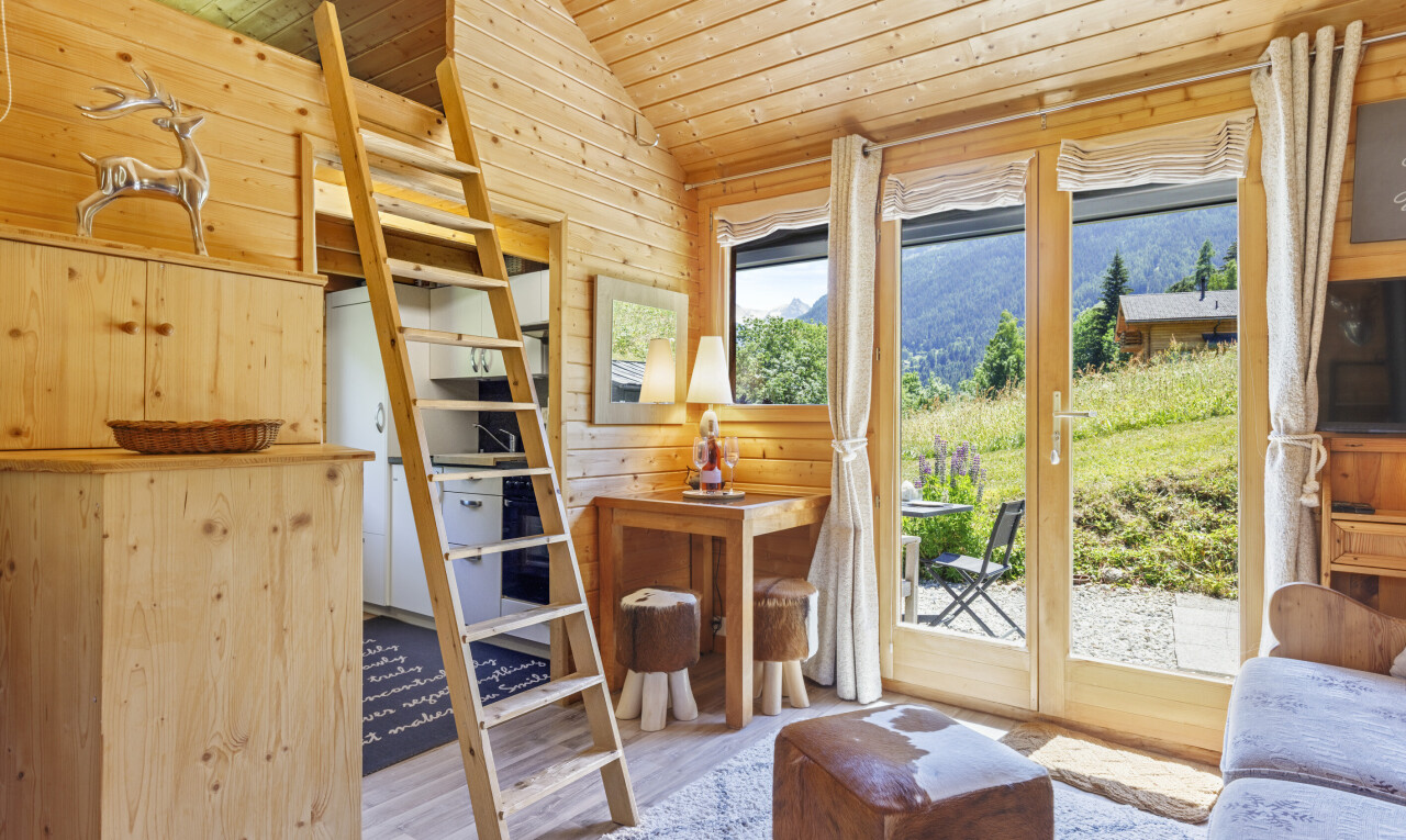 living room featuring a vaulted wood ceiling, light wood finished floors, and wooden walls