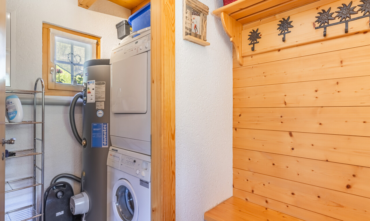 laundry area featuring stacked washer and clothes dryer, water heater, and wooden walls