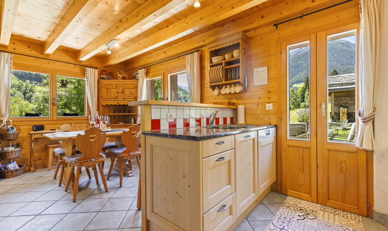 kitchen featuring light tile patterned floors, light wood finish cabinetry, plenty of natural light, wooden walls, and track lighting