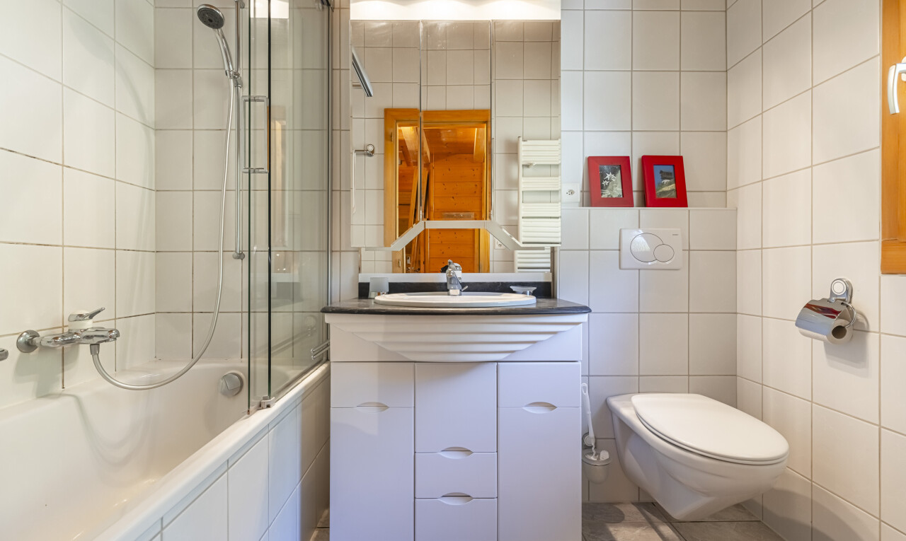 bathroom with tile walls, tiled shower / bath combo, light tile patterned floors, vanity, and radiator heating unit