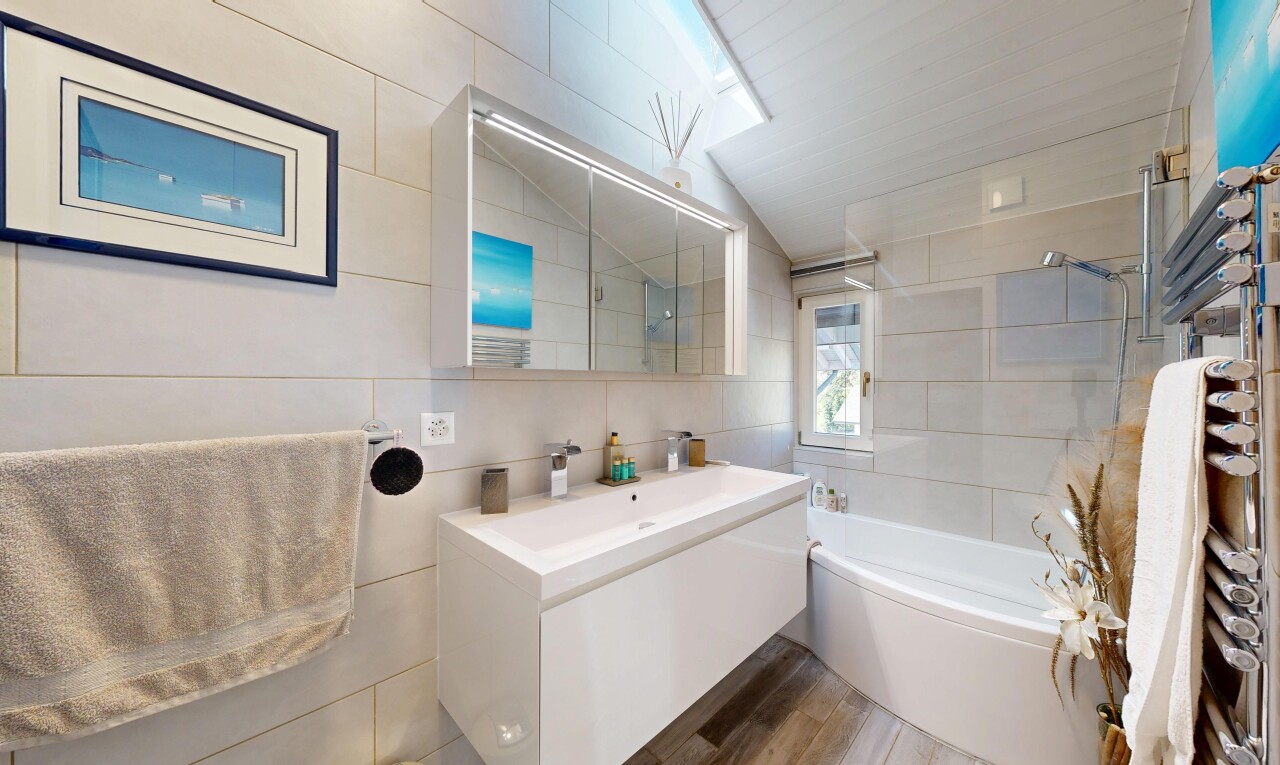 bathroom featuring tile walls, vanity,  shower combination, wood finished floors, and lofted ceiling