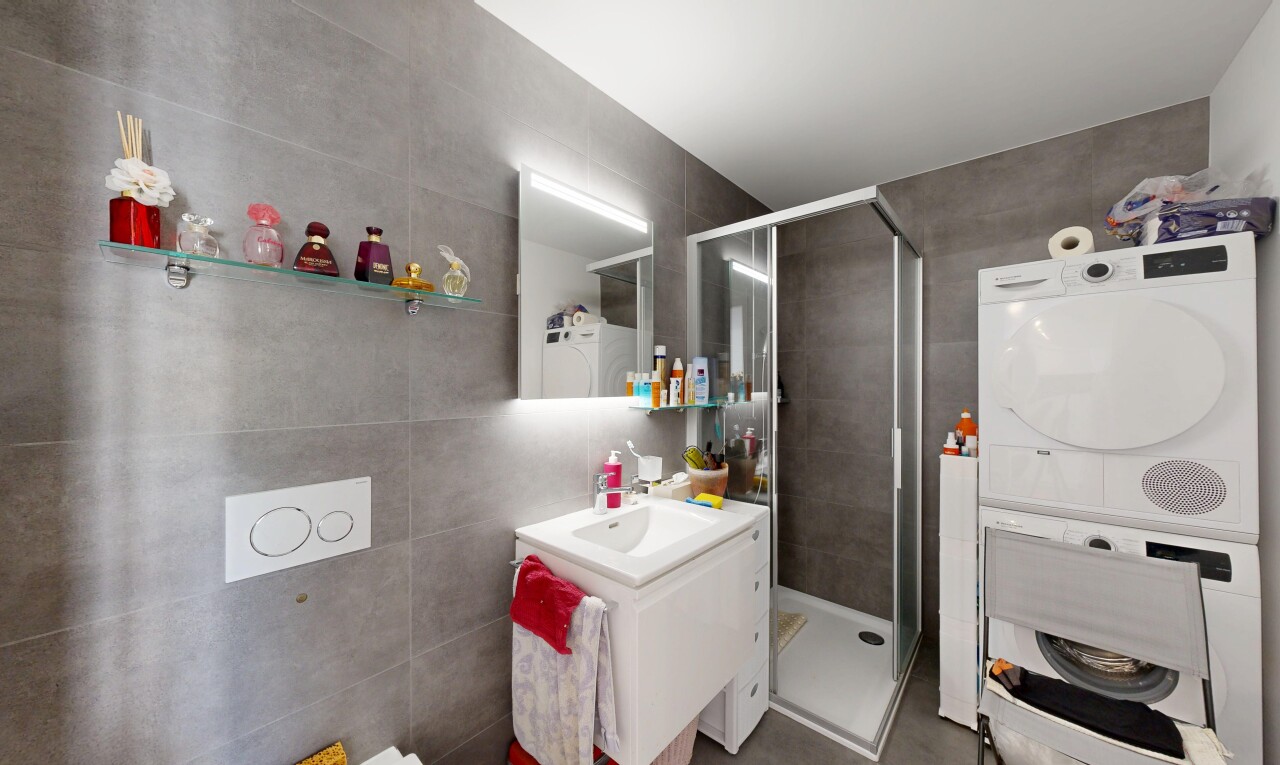 salle de bains avec tile wall, mur en carrelage, douche, lavabo (ou coiffeuse selon le contexte), et salle de bain complète