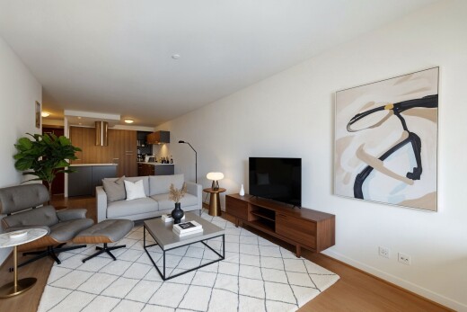 salon avec télévision, cloison sèche, drywall, sol en finition bois, et wood finish floor