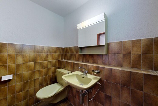 salle de bains avec toilette, inside property, miroir, évier, et mur en carrelage