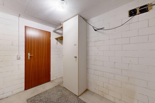couloir avec mur en blocs de béton, concrete block wall, inside property, sol en béton, et concrete floor