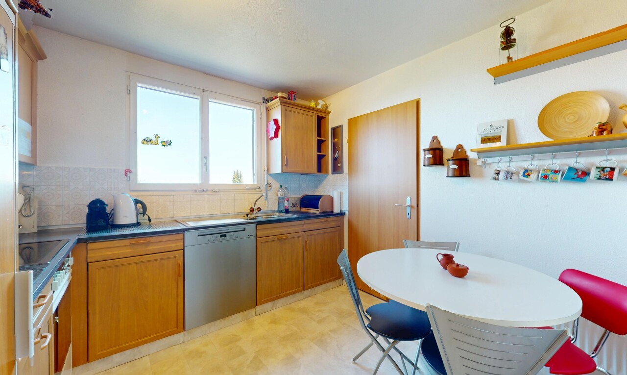kitchen with stainless steel dishwasher, light floors, brown cabinetry, open shelves, and decorative backsplash