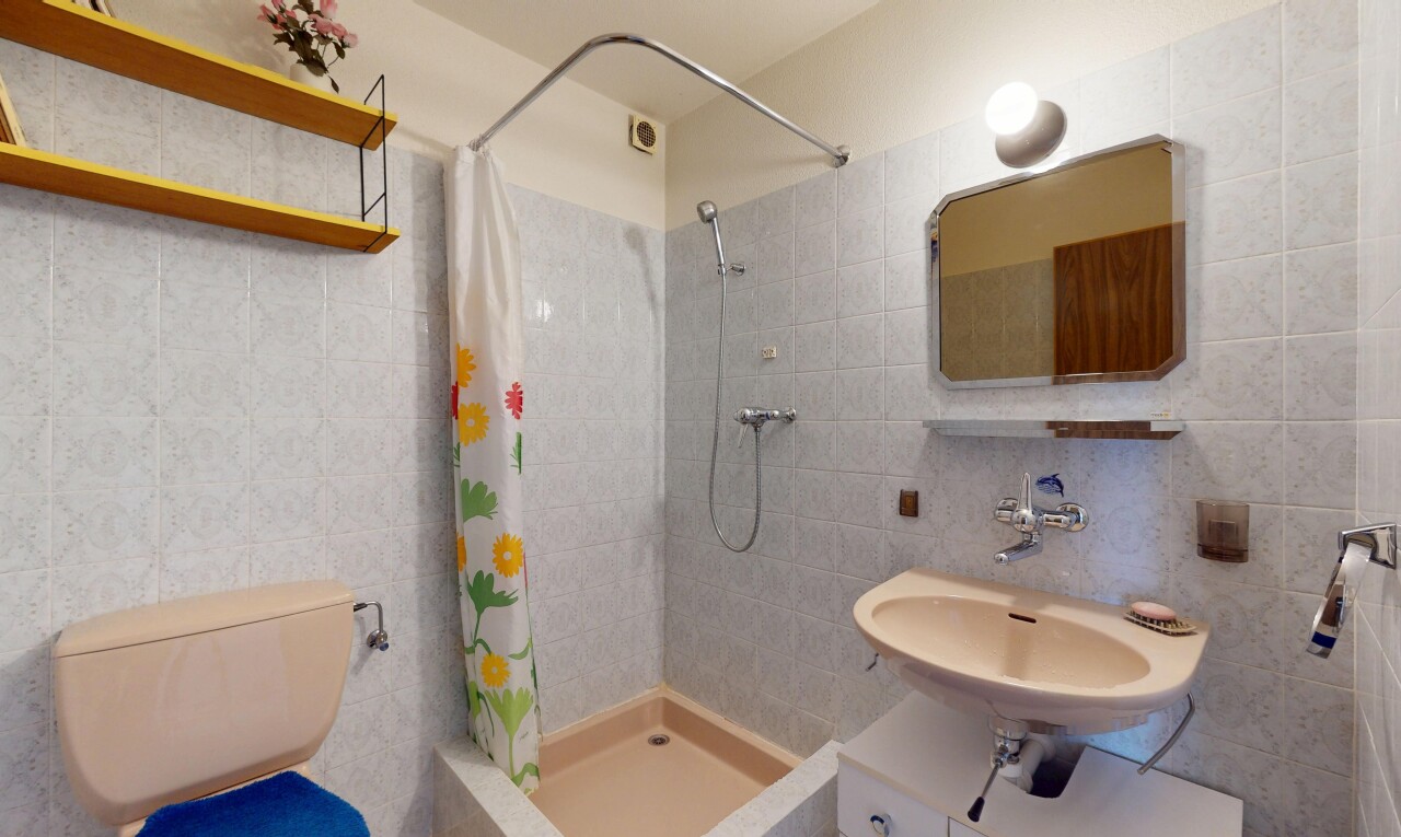 bathroom featuring a sink, tile walls, tiled shower, and toilet