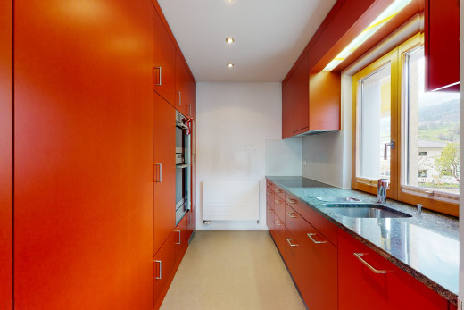 küche mit natürlichen licht, ofen, braunen schränken, dunklen steinplatten und helle böden