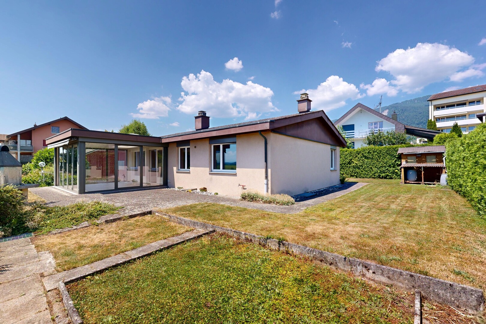 outdoor house featuring a sunroom, a yard, stucco siding, and a chimney