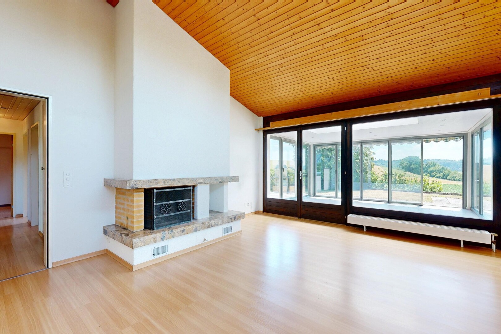 unfurnished room featuring a vaulted wooden ceiling, a fireplace with raised hearth, and light wood-style floors