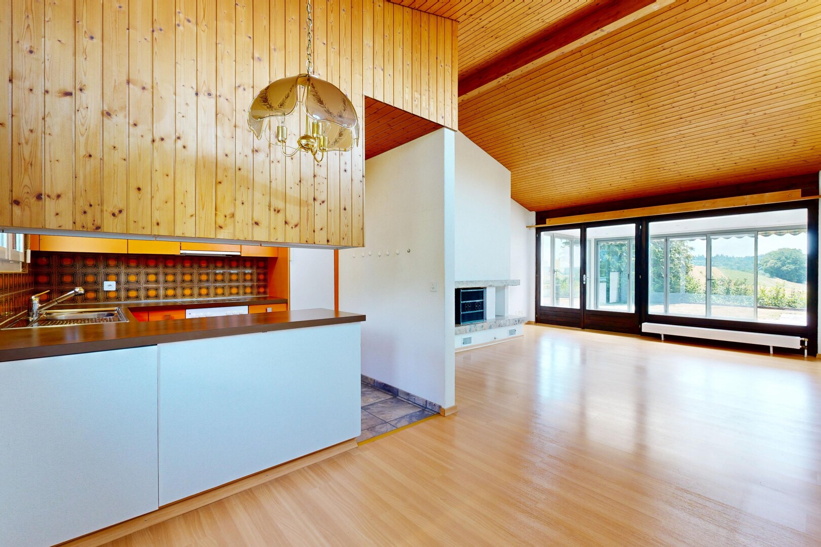 kitchen with a fireplace with raised hearth, light wood-style flooring, a chandelier, open floor plan, and a vaulted wooden ceiling