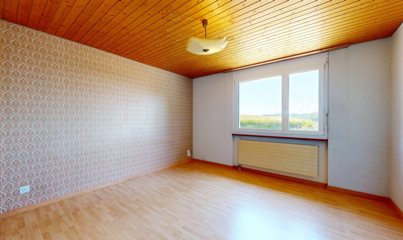empty room with wallpapered walls, light wood finished floors, radiator heating unit, and an accent wall