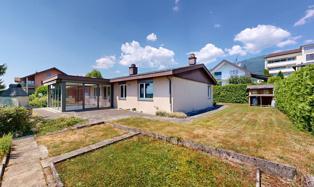 outdoor house featuring a sunroom, a yard, stucco siding, and a chimney