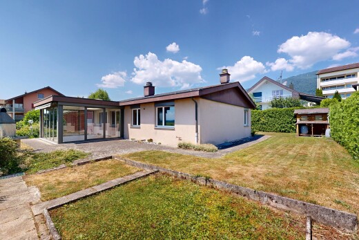 outdoor house featuring a sunroom, a yard, stucco siding, and a chimney